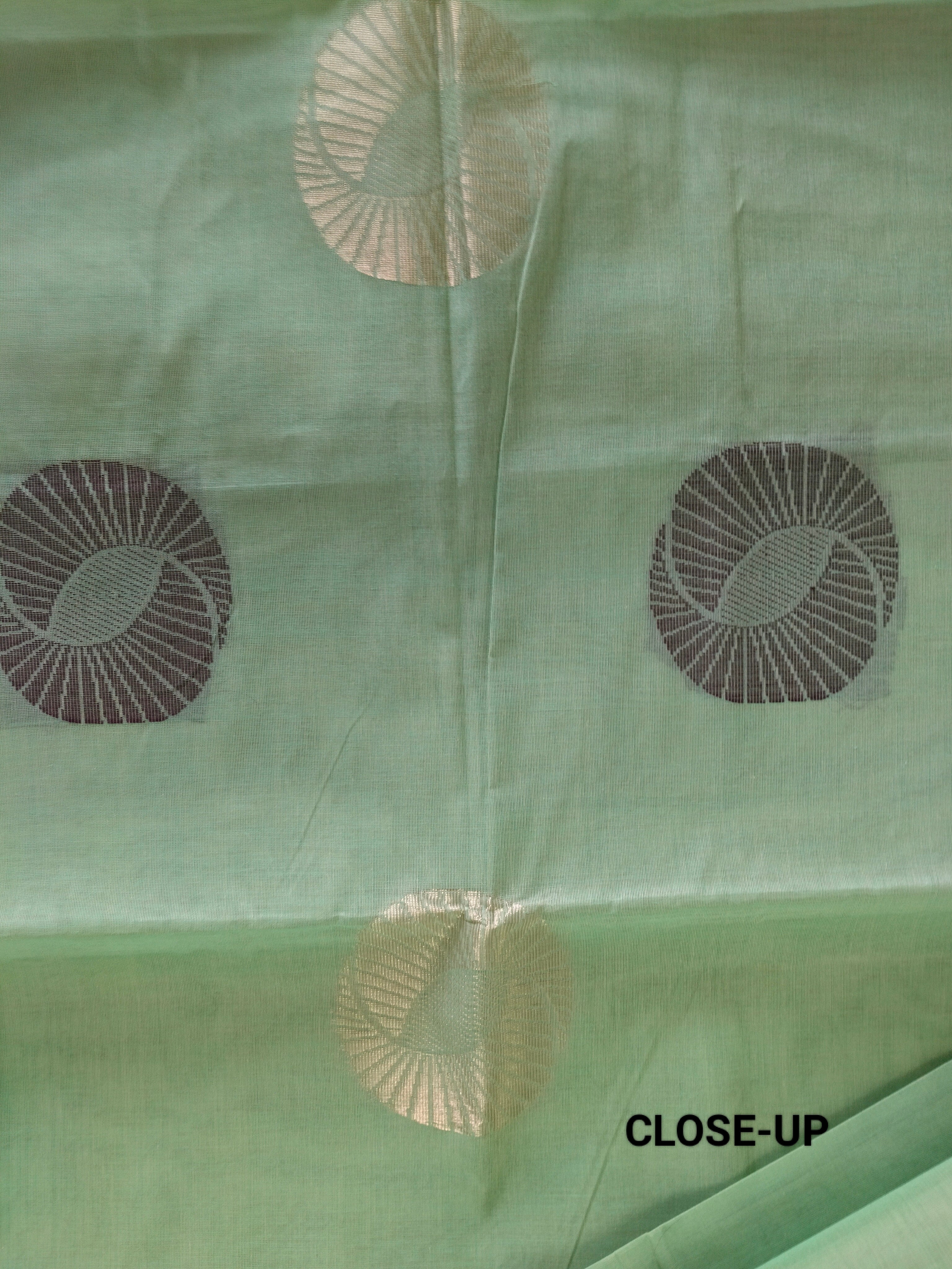 Pastel green cotton saree with alternate golden zari & black flower buttas