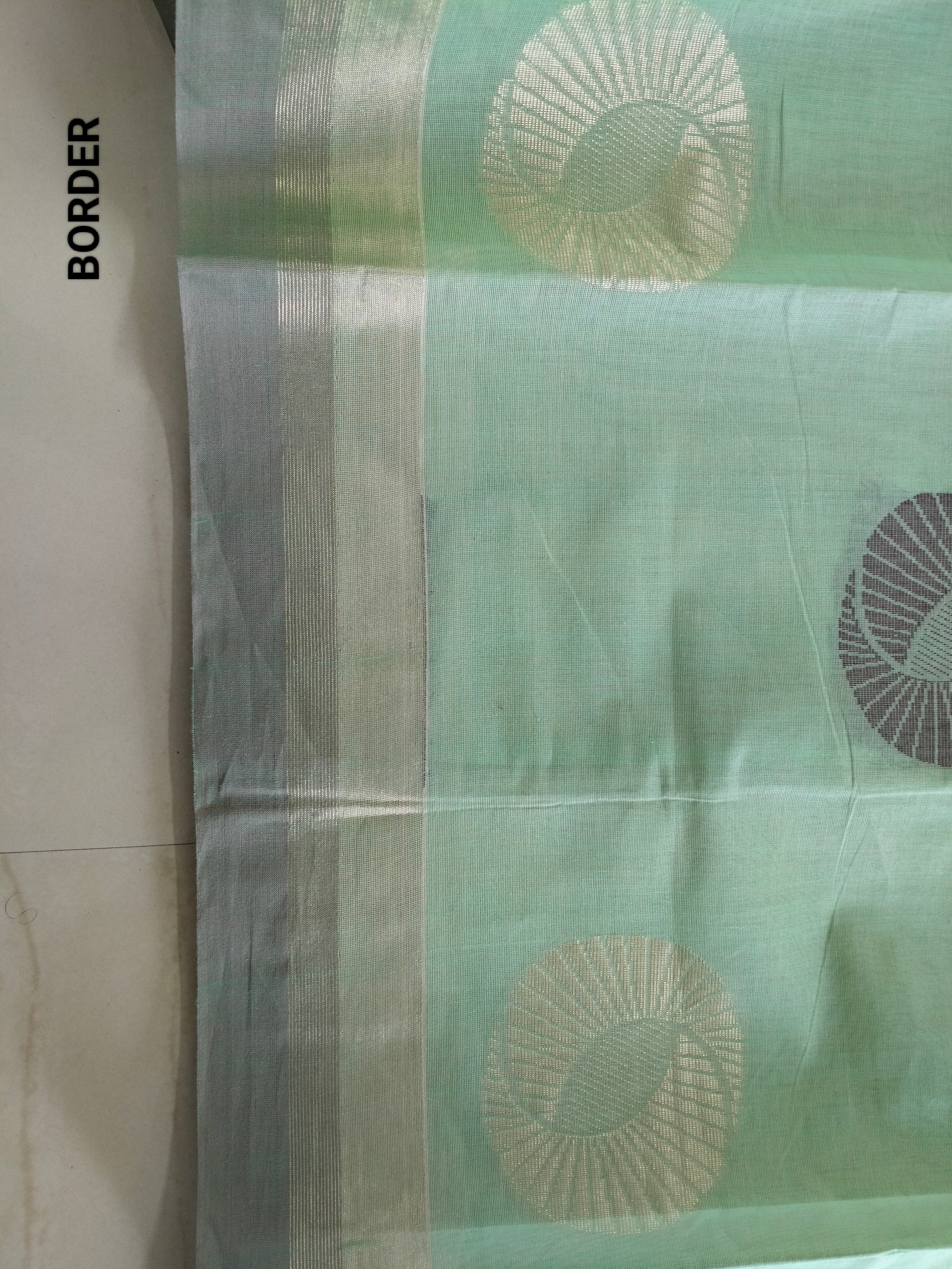 Pastel green cotton saree with alternate golden zari & black flower buttas